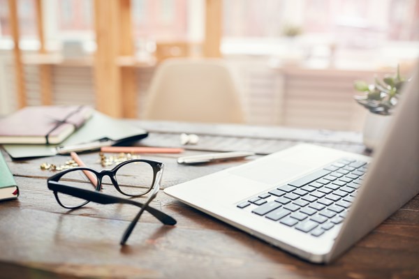 Skrivbord med glasögon och en laptop